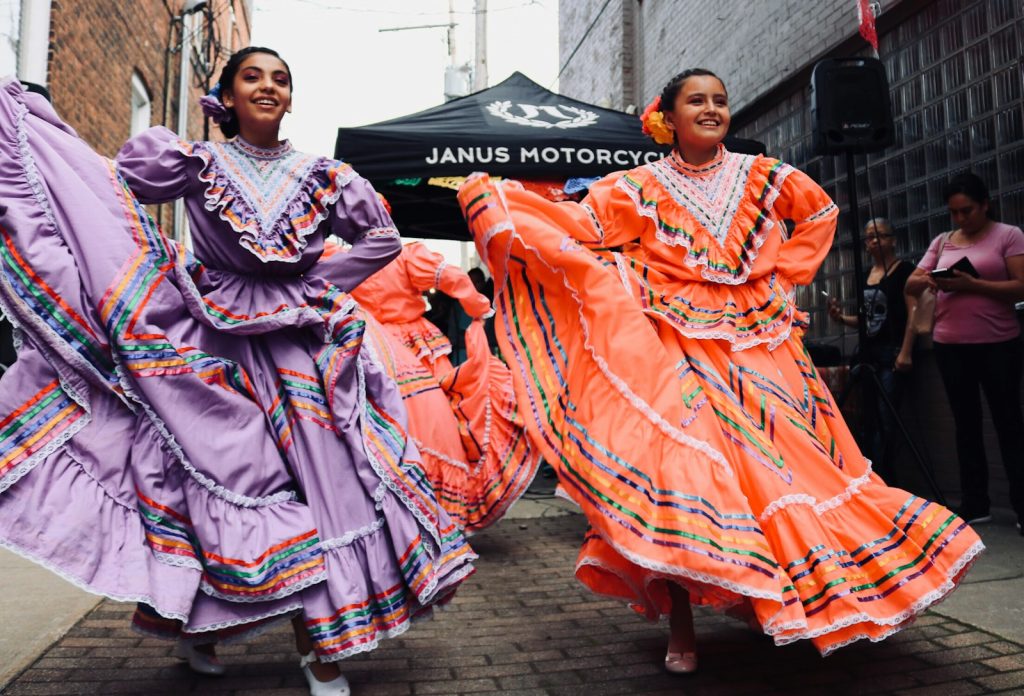 Traditional dancers in colorful dresses perform festive dance on a lively street stage